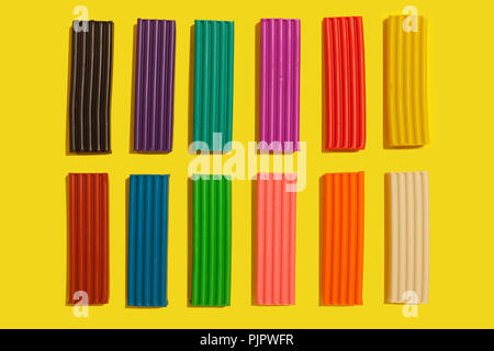 Set of colorful plasticine sticks lying on a yellow background. modeling claying pieces for children play and creativity Stock Photo