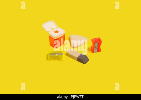 collection of different sharpeners and erasers lying on a yellow background. concept of office stationary. free copyspace Stock Photo