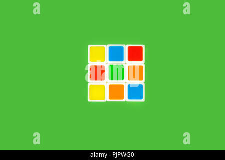 colorful plastic rubiks cube lying on a green background isolated. concept of developing toys Stock Photo