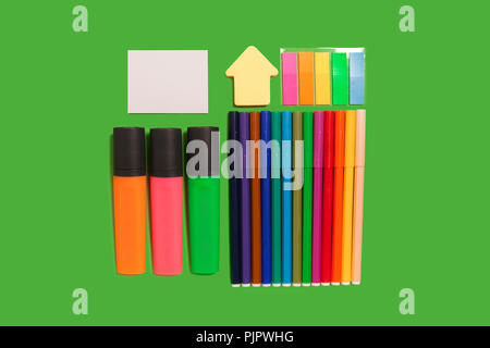 multicolored felt pens, markers, stickers and watercolour paints lying on a green surface. concept of drawing supplies Stock Photo