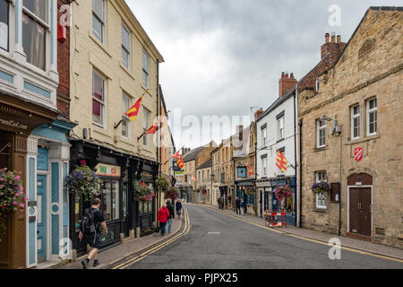 People walking along Market Street Hexham Northumberland with county flags flying Stock Photo