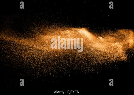 orange dust particles explosion on black background. Color powder dust splash. Stock Photo