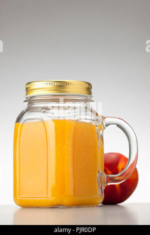 peach or nectarine juice in closed jar on white background Stock Photo
