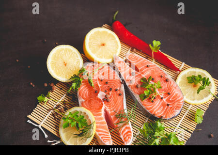 Salmon steaks with lemon and spices on black background with copy space text. Stock Photo