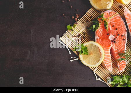 Salmon steaks with lemon and spices on black background with copy space text. Stock Photo