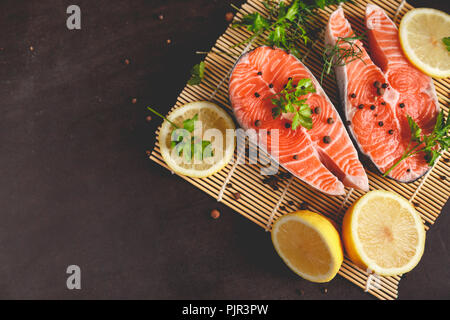 Salmon steaks with lemon and spices on black background with copy space text. Stock Photo