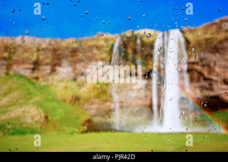 Looking through a raindrop covered window to a beautiful waterfall. Stock Photo