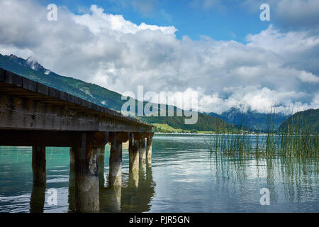 View of the lake near St. Wolfgang with a wooden pier and Alps mountains background, under a blue sky with clouds on a sunny day Stock Photo