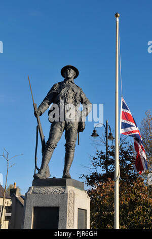 Memorial to soldiers killed during World War 1 beside a flagpole flying the Union Jack flag at half mast. Stock Photo