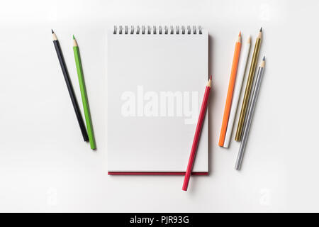 Design concept - Top view of red spiral notebook and many color pencil collection isolated on white background for mockup Stock Photo