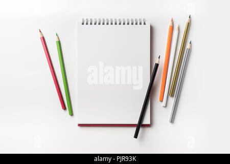 Design concept - Top view of red spiral notebook and many color pencil collection isolated on white background for mockup Stock Photo