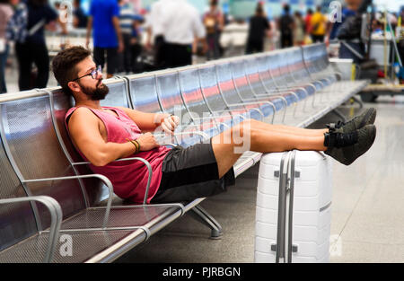 Man sleeping while waiting for transportation on the train station Stock Photo