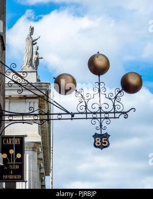 Pawn broker's sign outside a restaurant in Dublin Ireland with the symbolic three golden balls above the street with St Marys cathedral portico beyond Stock Photo