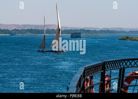 Traditional working sailing ship with old sails with holes transporting large stones, Nile River, Egypt, Africa seen from cruise ship deck Stock Photo