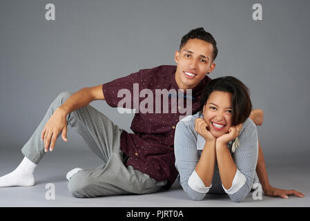 Happy young latin couple looking in to camera isolated on studio background Stock Photo