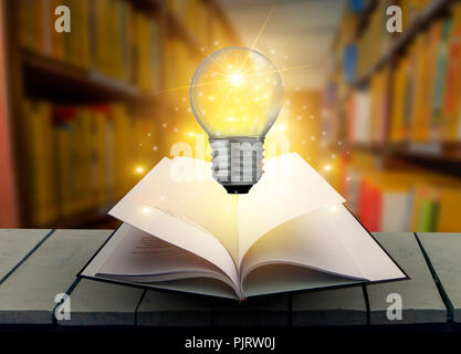 The book Light bulb is on the table. Wood in the library Book and light bulb Old tattered book on a wooden table Reading by candlelight Vintage compos Stock Photo