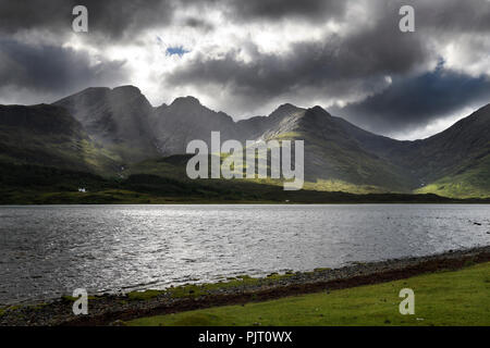 Sun rays on Bla Bheinn mountains outlier of the Black Cuillin with dark clouds and Loch Slapin from Torrin Isle of Skye Scotland UK Stock Photo