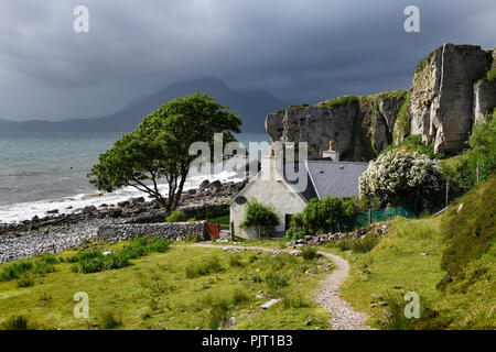 House under cliff at Elgol beach with Red Cuillin Mountains under clouds at Loch Scavaig Scottish Highlands Isle of Skye Scotland UK Stock Photo