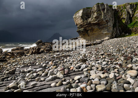 Smooth boulders of Elgol beach at Port na Cullaidh with Red Cuillin Mountains under clouds on Loch Scavaig Isle of Skye Scotland UK Stock Photo