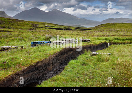 Trenches cut into deep Peat of wetland moors near Drinan on Isle of Skye Scotland with Loch Slap and Beinn Dearg Mhor and Beinn Na Caillich peaks Stock Photo