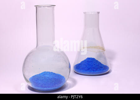 Florence flask closeup, in front of Erlenmeyer flask. Both with copper sulfate. Magenta hue of backgrounds Stock Photo