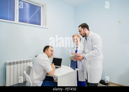 Medical staff discussing over medical reports using laptop and tablet pc. Healthcare professionals having discussion in hospital office. Stock Photo