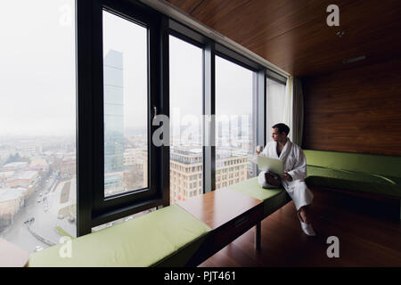 Happy man drinking coffee and using laptop in bed in the morning Stock Photo