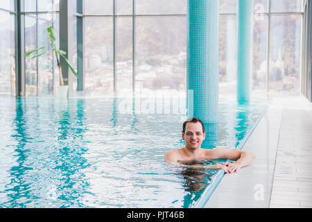 Shot of a handsome young happy man in the indoor swimming pool Stock Photo