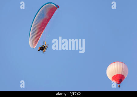 Motorized paraglider and hot air balloon against a beautiful blue sky Stock Photo