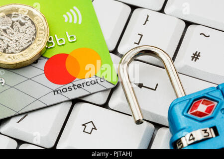 Lloyds bank Mastercard contactless credit card and one pound coin on a keyboard with enter key and open padlock. Online shopping security concept. UK Stock Photo