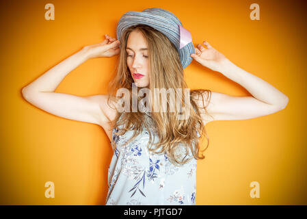 Natural light portrait of a young blonde woman wearing a hat looking away from camera Stock Photo