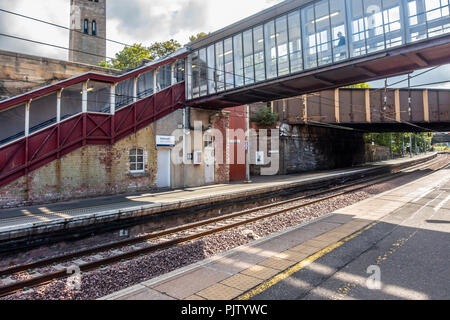 Part of Motherwell Railway Station, North Lanarkshire, Scotland, showing a railway track, two platforms, a passenger bridge, a road bridge, and the to Stock Photo