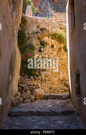 Traditional village alleyway with stone walls, flowers and lamps Stock Photo