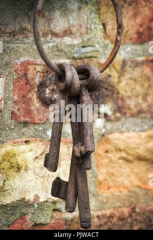 Three rusty keys having on a hook on a wall Stock Photo
