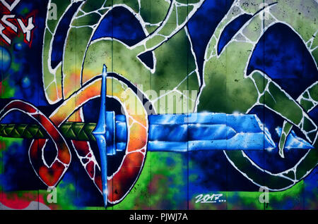 A fragment of detailed graffiti of a drawing made with aerosol paints on a wall of concrete tiles. Background image of street art with a fairy-tale cr Stock Photo