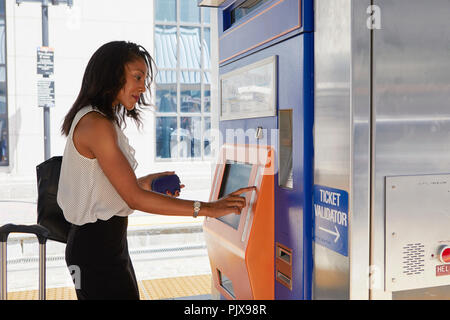 Businesswoman buying train ticket at machine Stock Photo