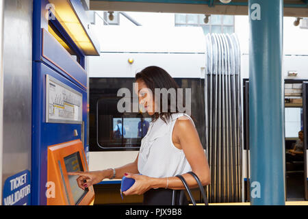 Businesswoman buying train ticket at machine Stock Photo