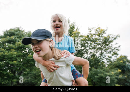 Children playing piggyback in park Stock Photo