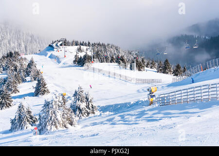 Ski resort, ski slope, ski lift, pine trees and fog mountains panorama Stock Photo