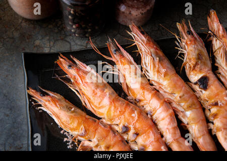 Grilled shrimp with charcoal flaming fire serve in black dish with dark shadow lighting. Stock Photo