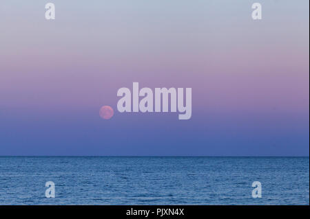 Full moon, a lunar phase, above the sea. Late evening up North. Colorful sky. Stock Photo