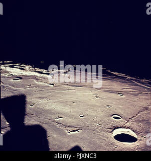In Lunar Orbit - (FILE) -- This west-looking image of the landing site in the southwestern Sea of Tranquility (Mare Tranquilitatis) was taken from the lunar module one orbit before descent, while still docked to the command module. The Tranquility base site is near the shadow line, just to the right of center. The large crater at the lower right is the 23 km diameter Maskelyne, centered at 2.2 N, 30.1 E. The large black object in the lower left is not a shadow but a LM thruster in the camera field of view. Credit: NASA via CNP /MediaPunch Stock Photo
