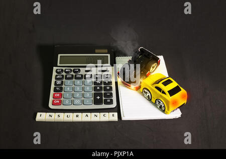 Car insurance concept, toy cars representing a car accident beside a calculator Stock Photo