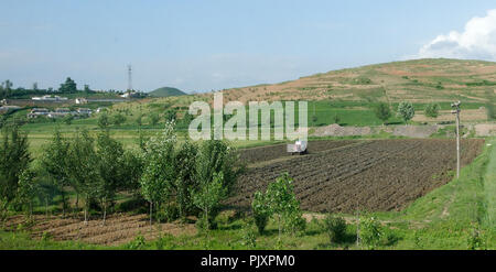 Lone tractor ploughing an empty field. North Korea Stock Photo