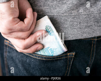 his hand put russian rubles in jeans pocket or take out from pocket Stock Photo