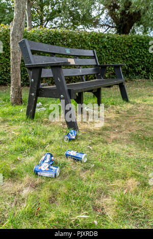 Empty beer cans on grass next to park bench Stock Photo