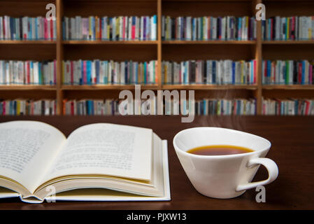 a book open on the desk with a cup of coffee. Stock Photo