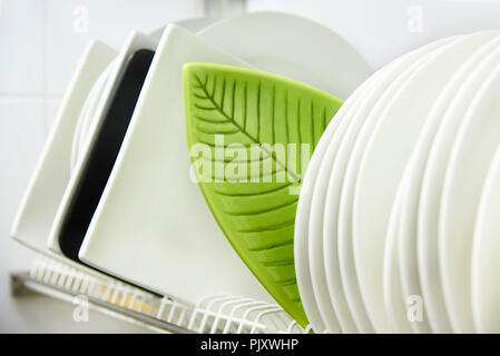 Different clean plates in dish drying rack close-up. Stock Photo