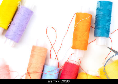 Overhead photo of thread spools of various colors on white with a place for text Stock Photo