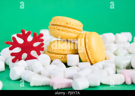 Yellow macaroons, marshmallow and red flake on green Stock Photo